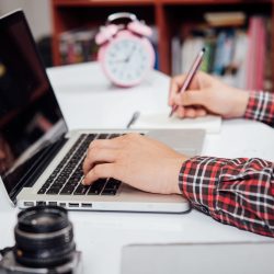 Close up young man working and smart phone and laptop on wooden desk in office